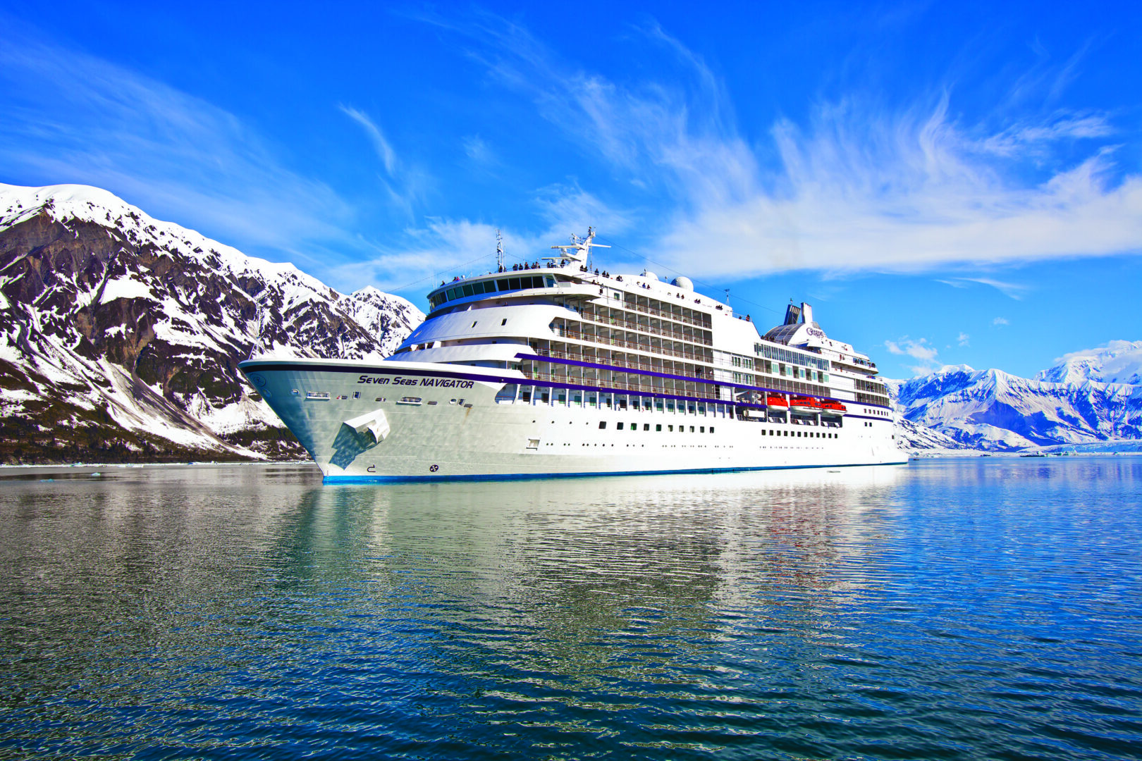 Cruise ship sailing near snowy mountains.