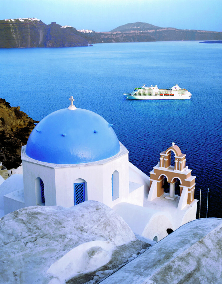 Blue dome church overlooking sea with cruise.