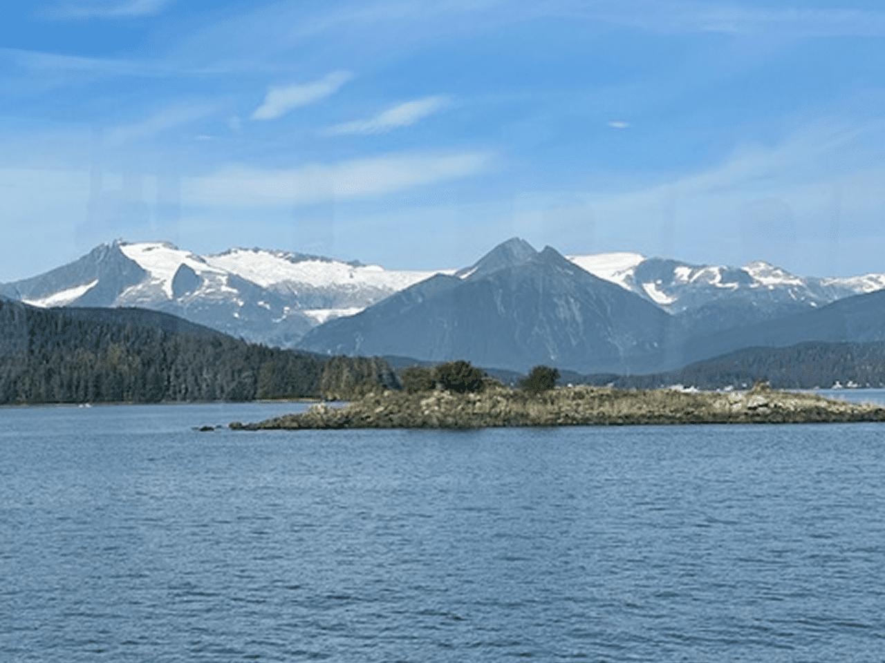 Snow-capped mountains and lake under blue sky.