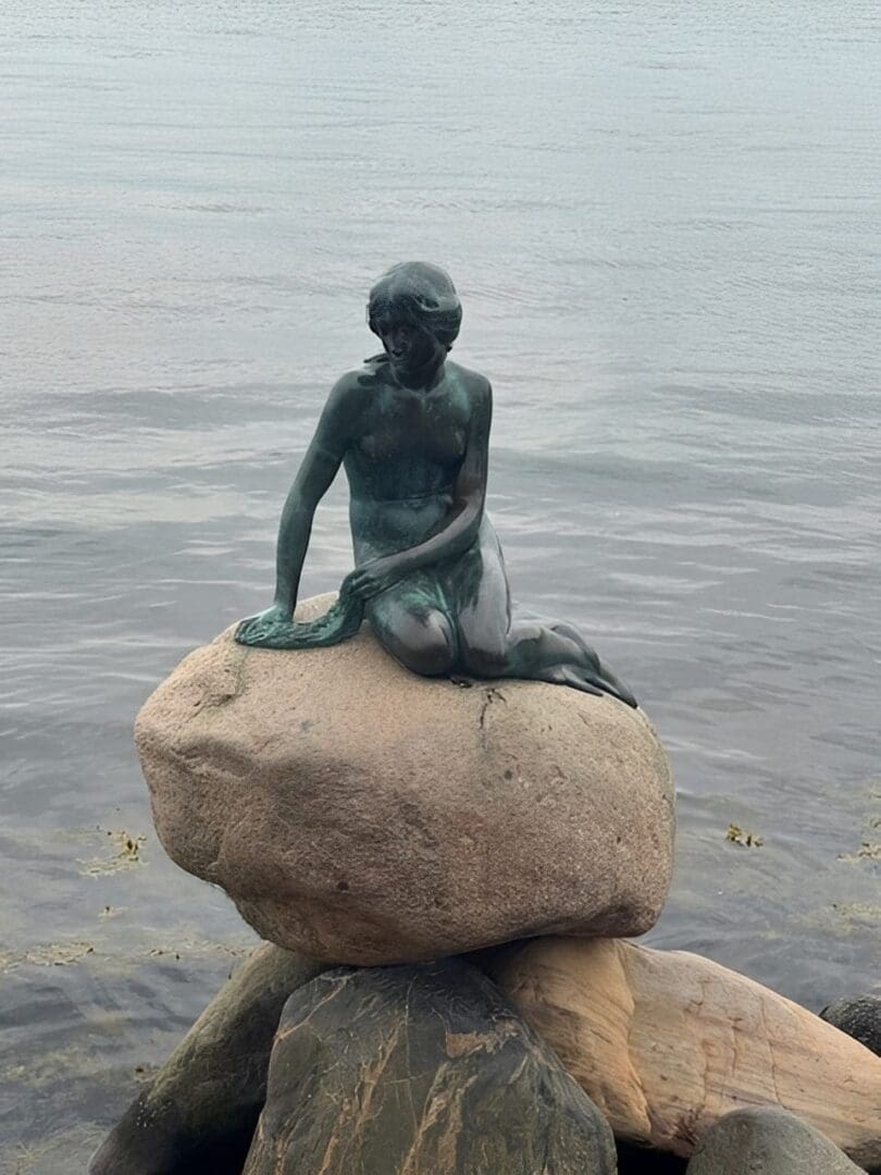 Mermaid statue sitting on a rock.