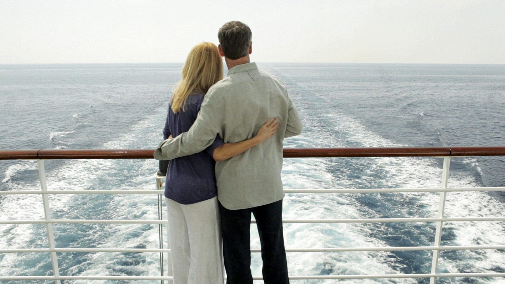 Couple hugging on cruise deck overlooking ocean