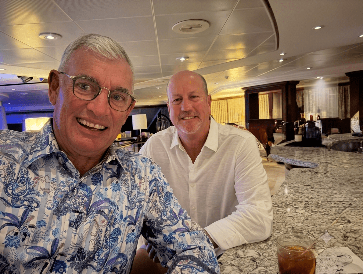 Two men smiling at a bar counter.